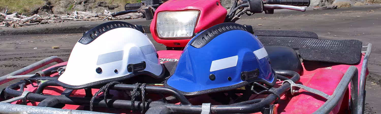 A white and blue Pacific Helmet ATV helmet sitting on the front of a red ATV